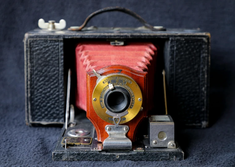 an antique camera is in its case and has two small cameras attached