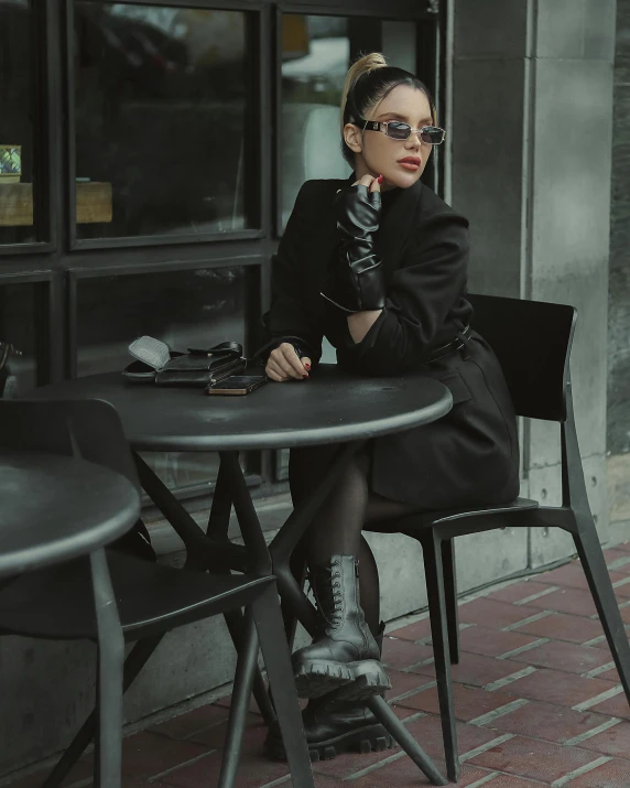 a woman sitting at a table wearing black gloves