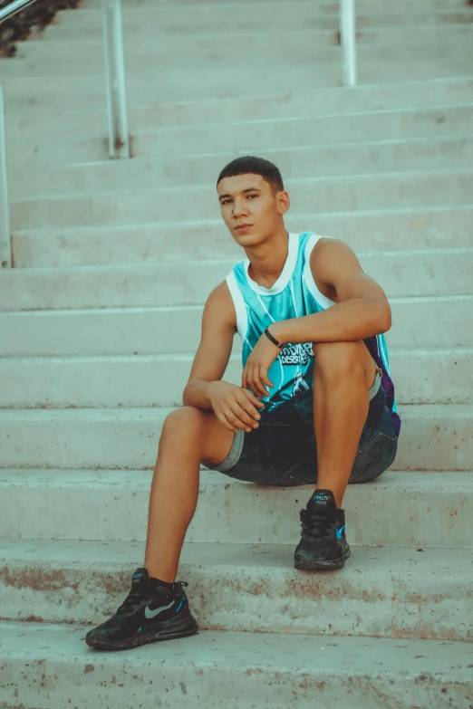 a young man sits on the steps with his legs crossed