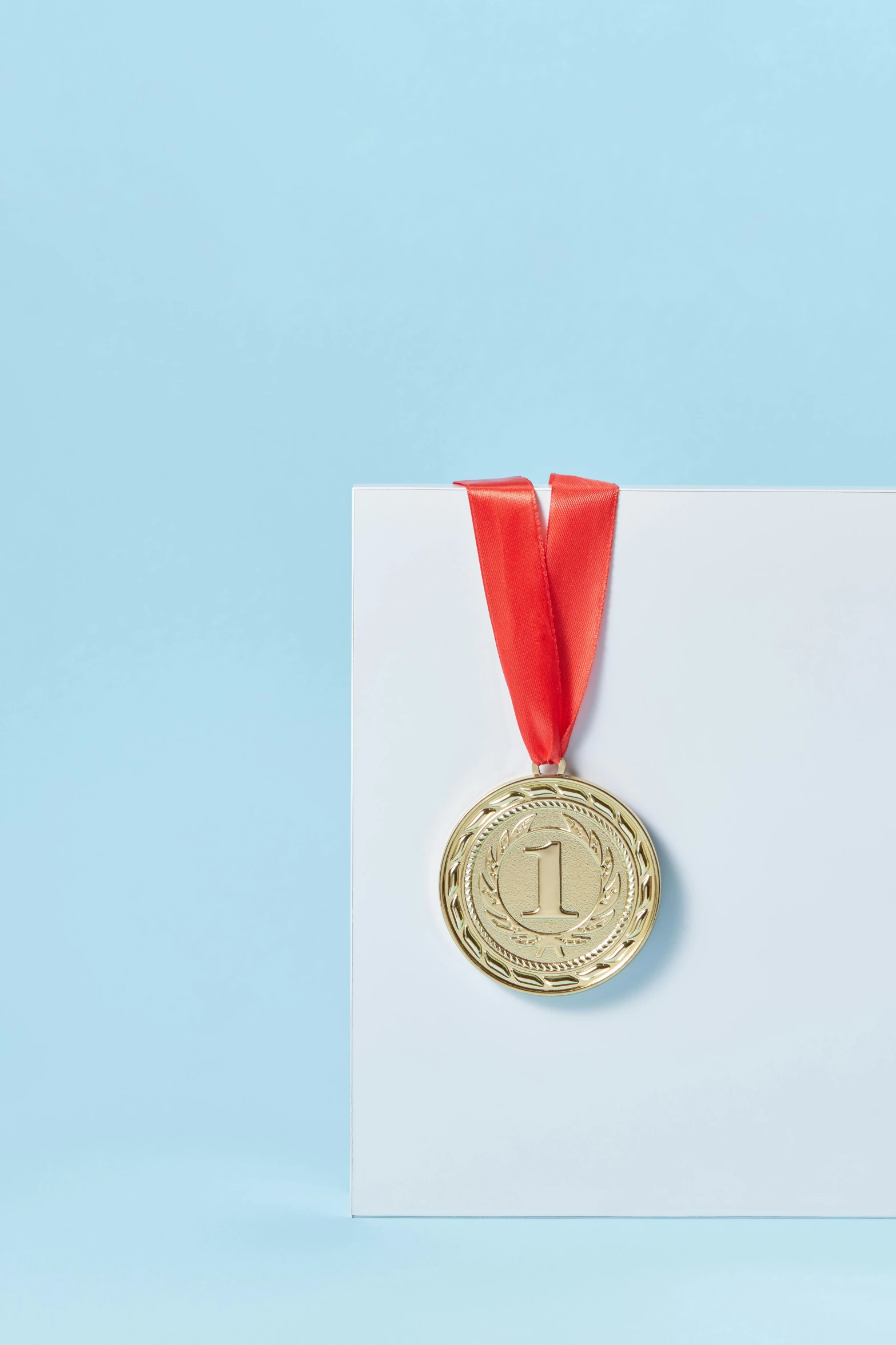 a gold medal on a white card with a red ribbon