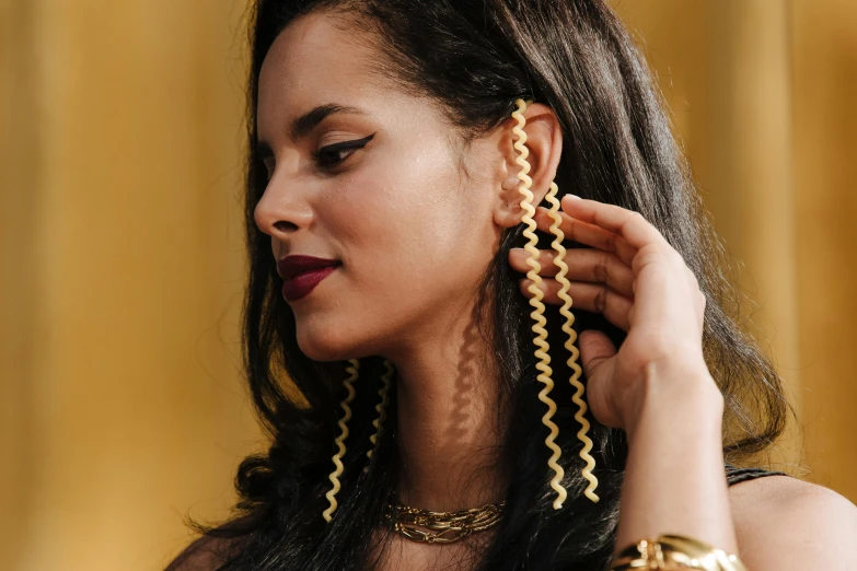 a woman adjusting gold earrings on her long black hair