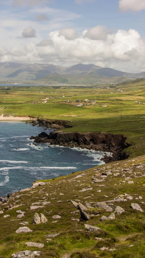 the rocky shore of an ocean with a few green hills