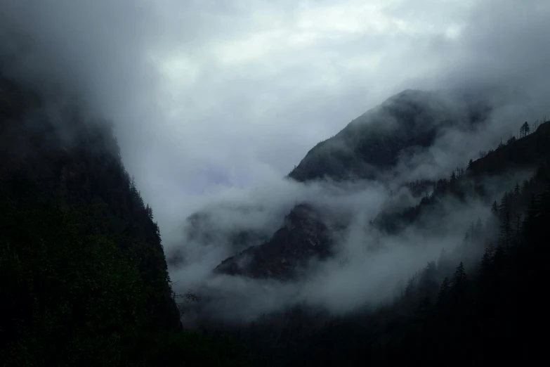 two tall mountains rise above a foggy forest