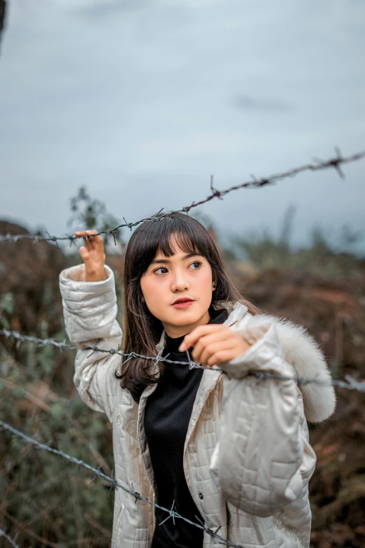 a girl standing behind a barbed wire fence