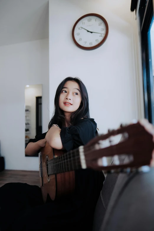 a woman that is sitting down with a guitar