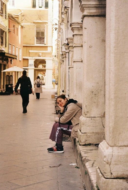 the girl is sitting on the curb next to the wall