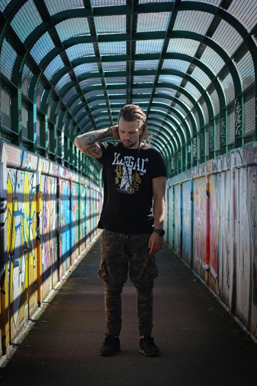 man standing under colorful graffiti painted ceiling in long tunnel