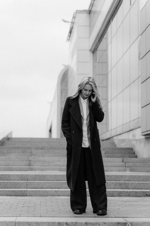 a woman leaning up on some steps holding her hair in the wind