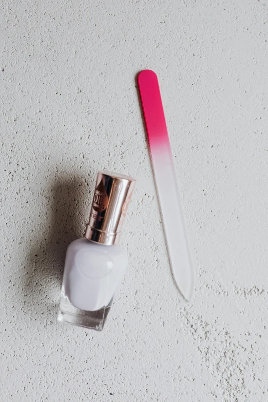 a pink brush is sitting next to a white bottle