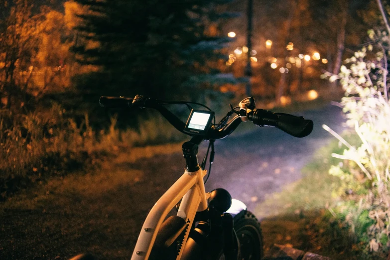 the bike has a phone on it and is parked near a road