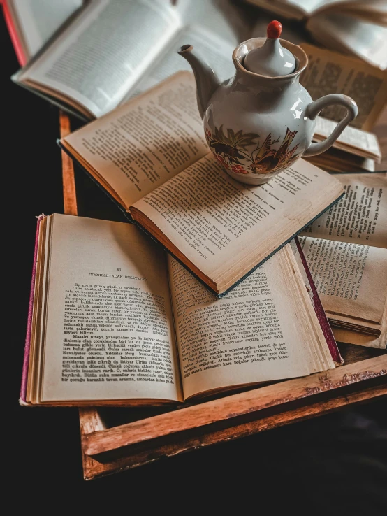 an open book with a teapot and four smaller books sitting on top of it