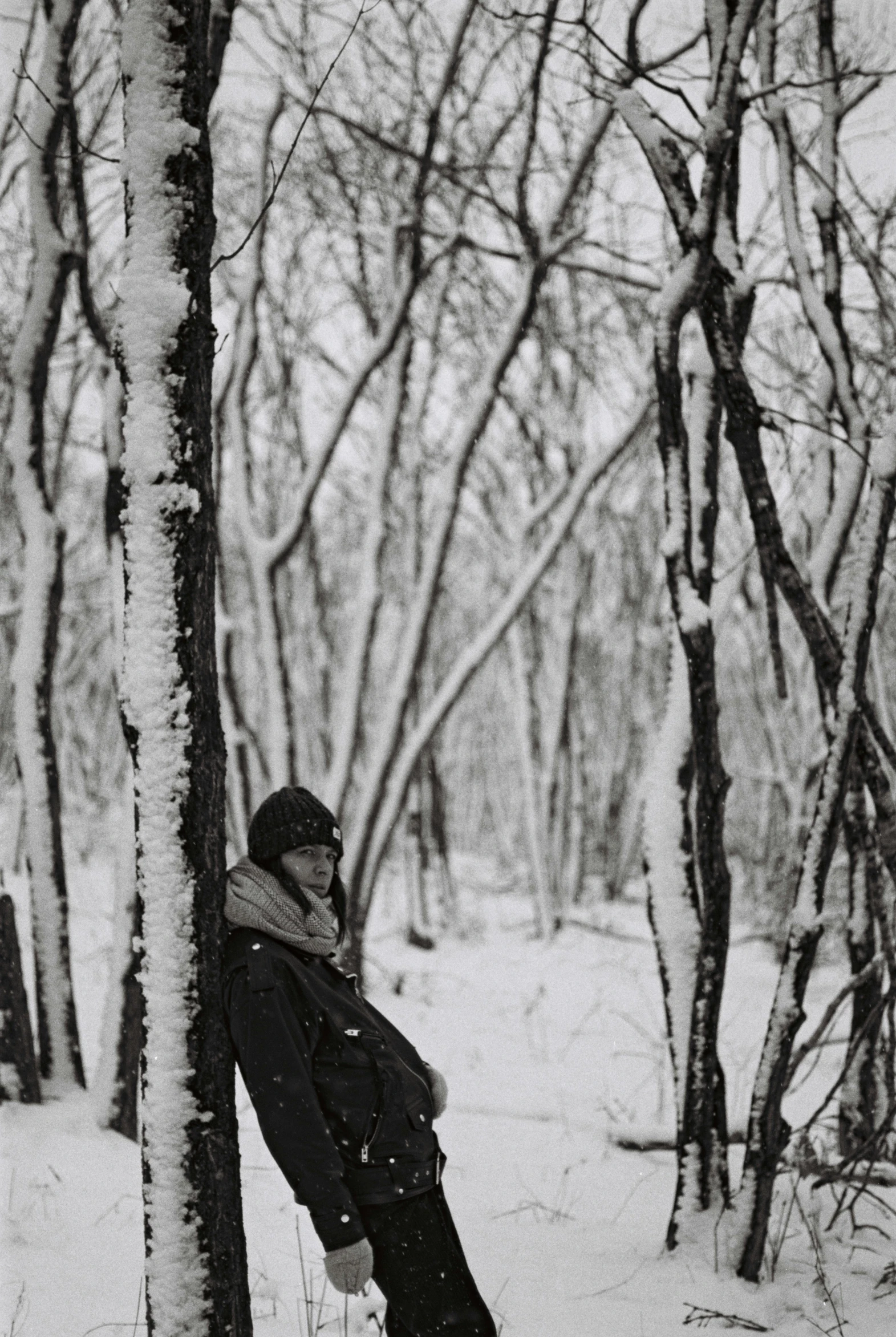 a  leans against a tree in a snowy woods