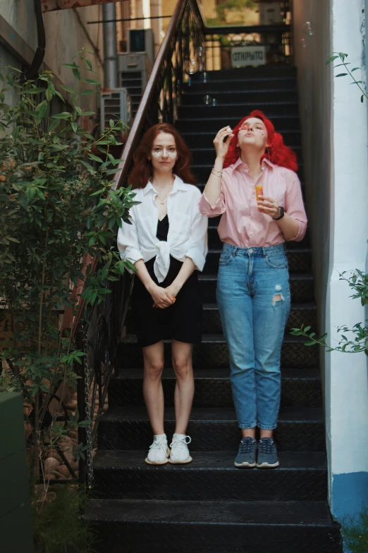 two women stand at the top of some stairs