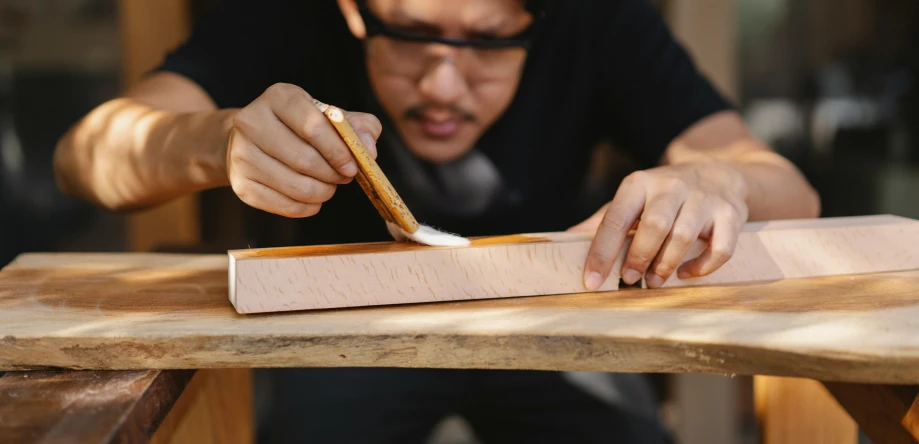 a man that is  some kind of material on a piece of wood