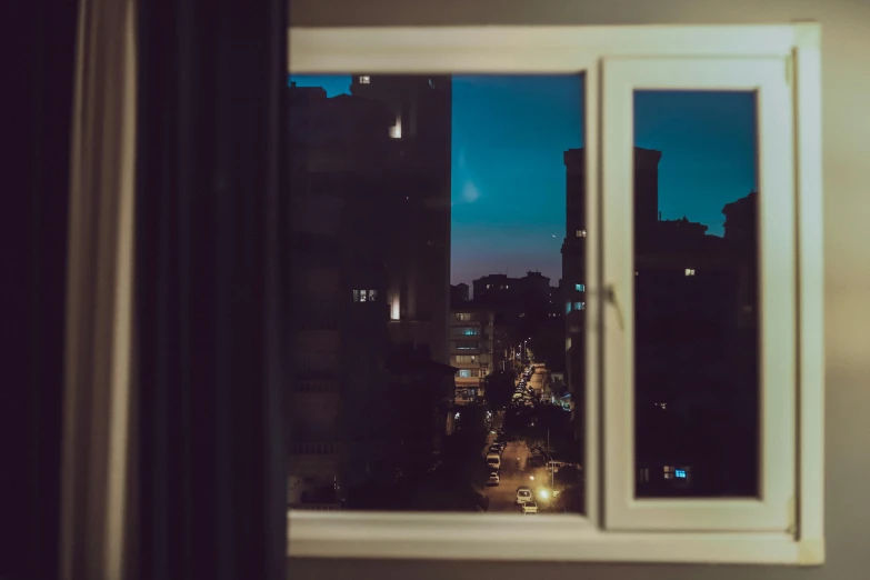 an open window reveals the city lights below