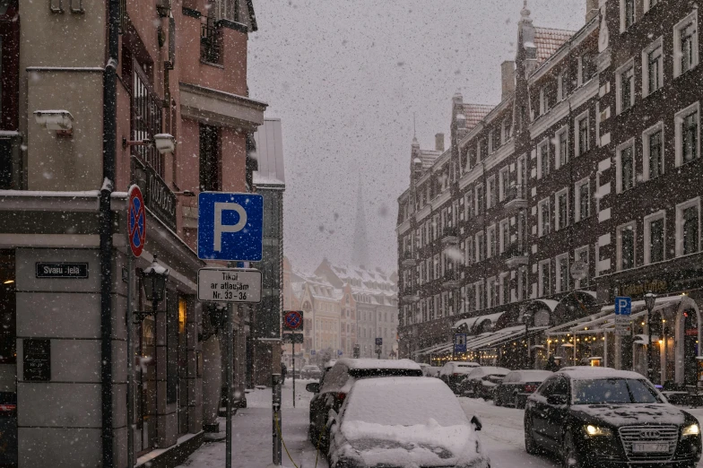 a snowy street lined with parked cars and traffic signs