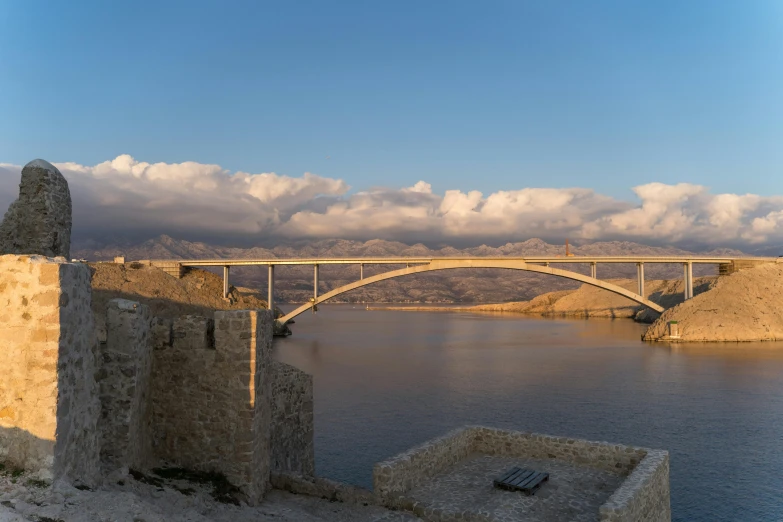 an old bridge sits over a very calm waterway