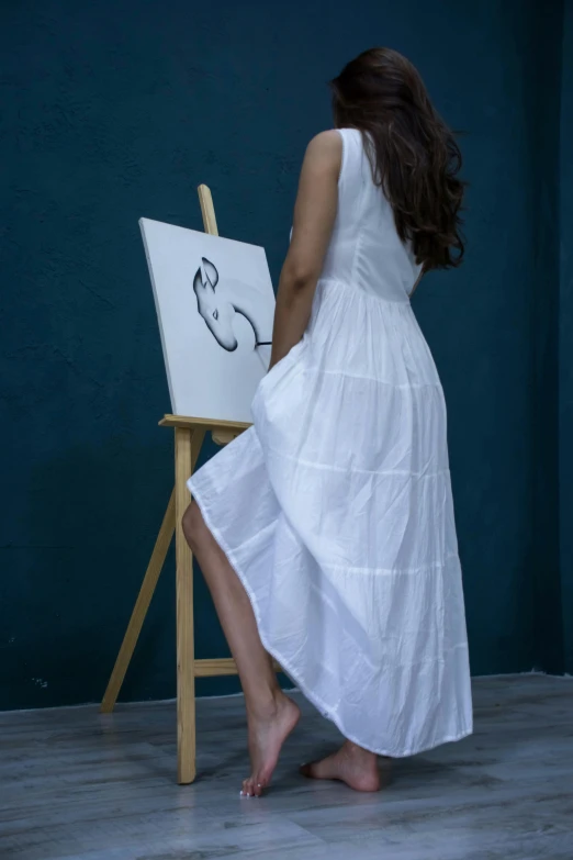 the woman is standing near an easel while painting