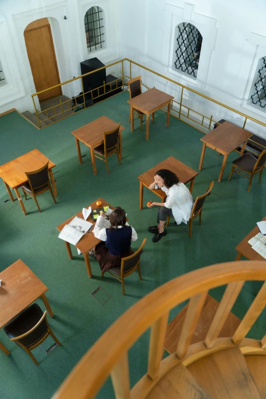 two people sitting at a desk in a very big room