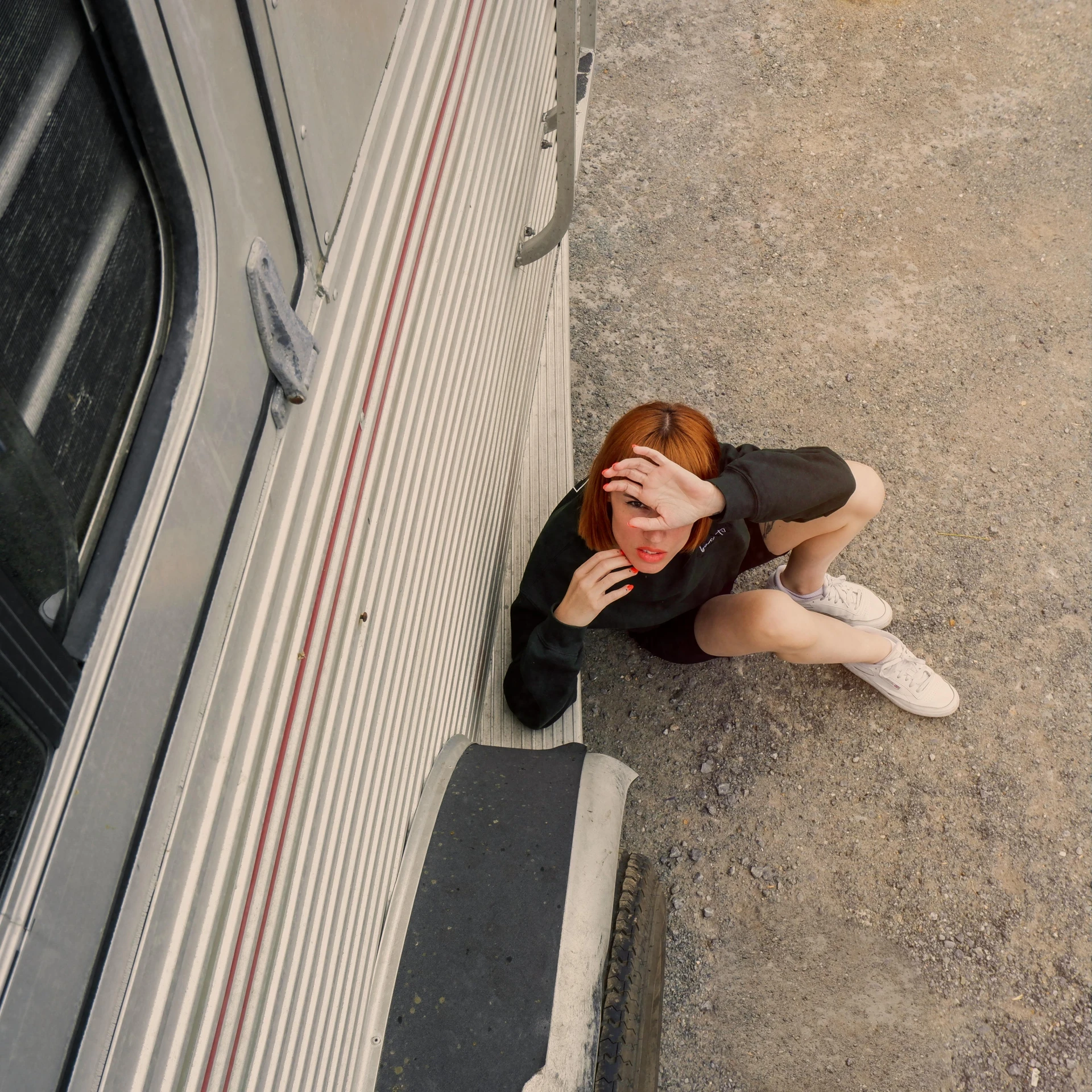 an aerial po of a woman covering her face on the side of a vehicle