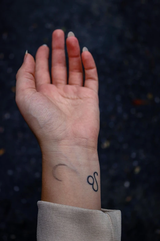 a female hand holds up her small black letter on her right wrist