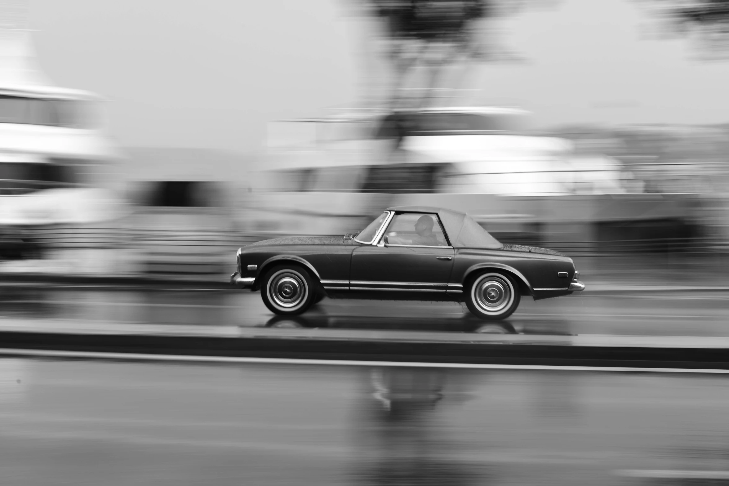 a black and white picture of an old car on the road