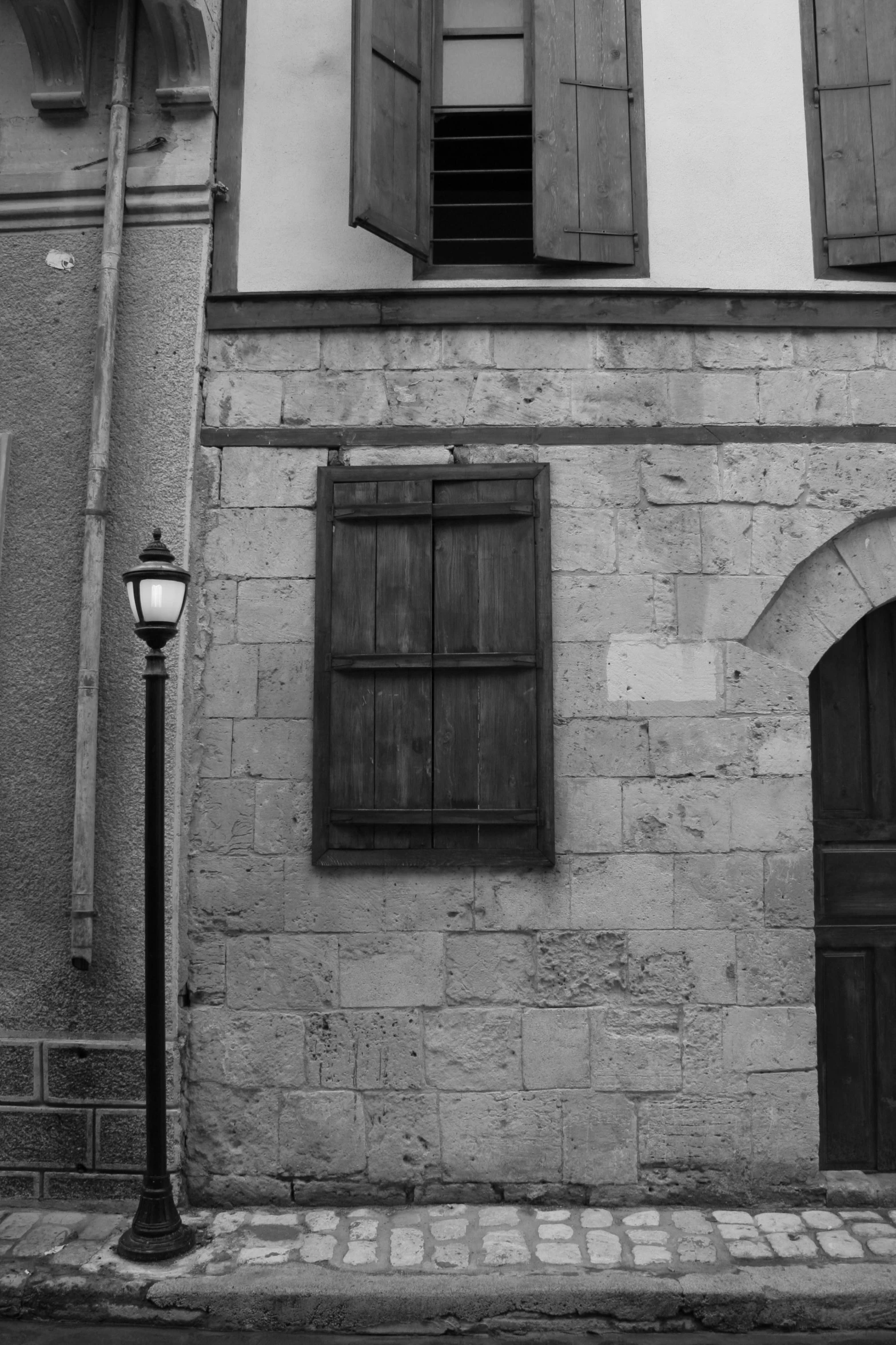 a stone building with shutters, lamppost and window