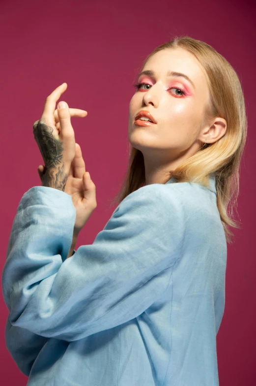 a blond woman in blue shirt with fingers crossed