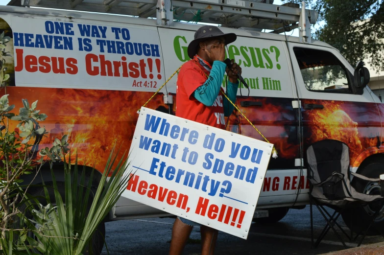 a woman in a cowboy hat holds up a sign