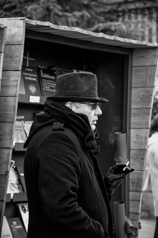 the man in the hat is smoking and looking at his cell phone