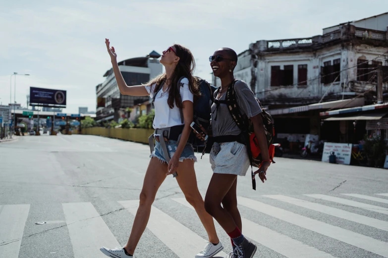 two people walking across a street holding hands