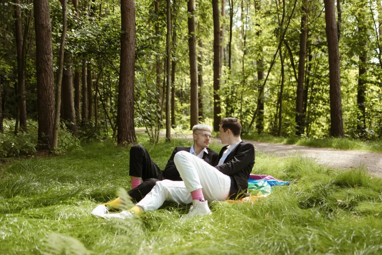 there are two men in suits sitting on a blanket