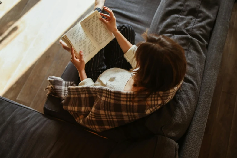 a woman reading on the couch while using her phone