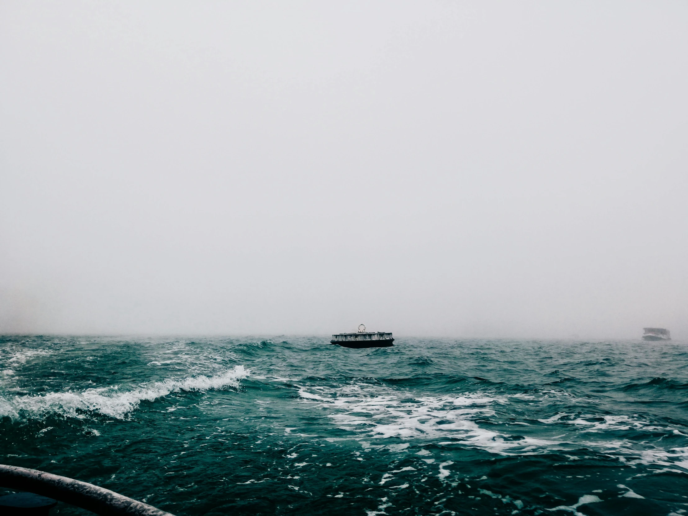 boats float in the water under an overcast sky