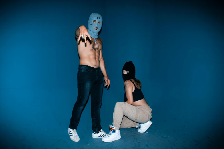 the person with the blue mask is squatting down while another person has their arms outstretched