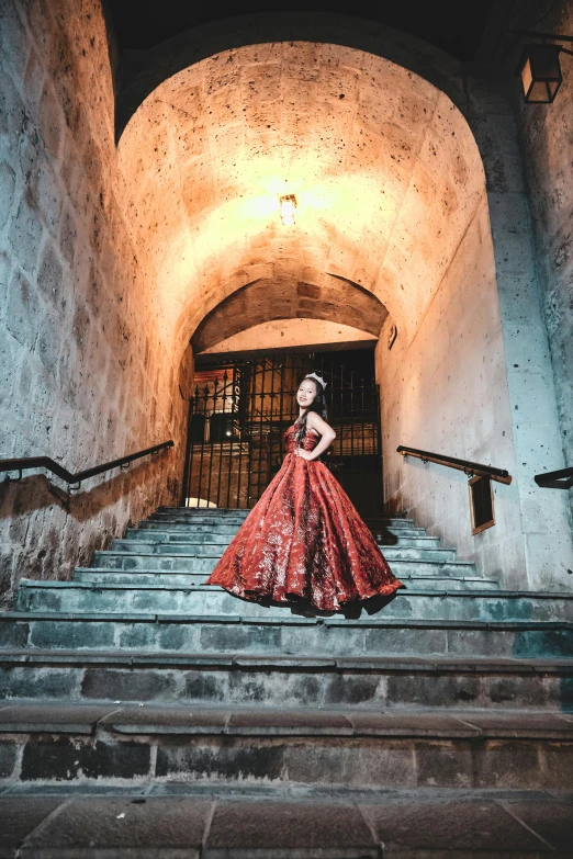 a woman in a long red dress stands on the stairs