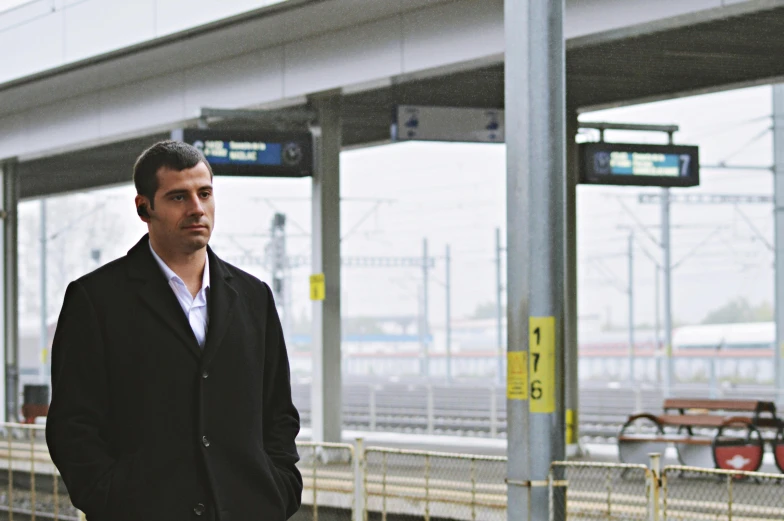 man standing on street waiting at train station