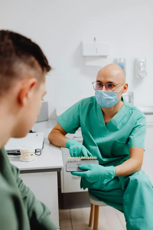 an adult patient showing a child how to brush his teeth