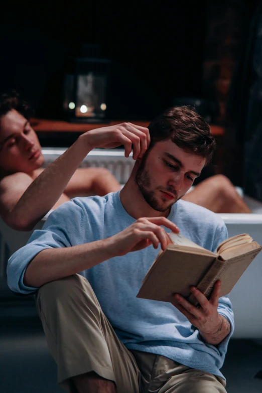 young man reading book while sitting on floor