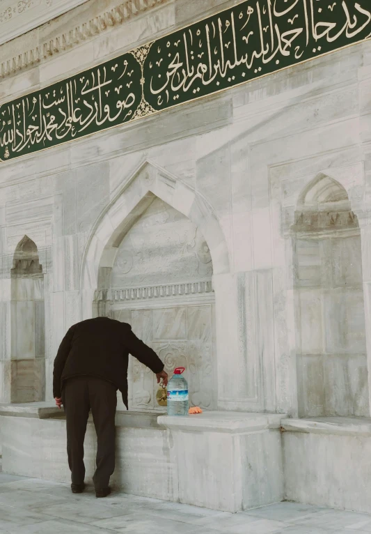 an old man leaning over a white stone wall