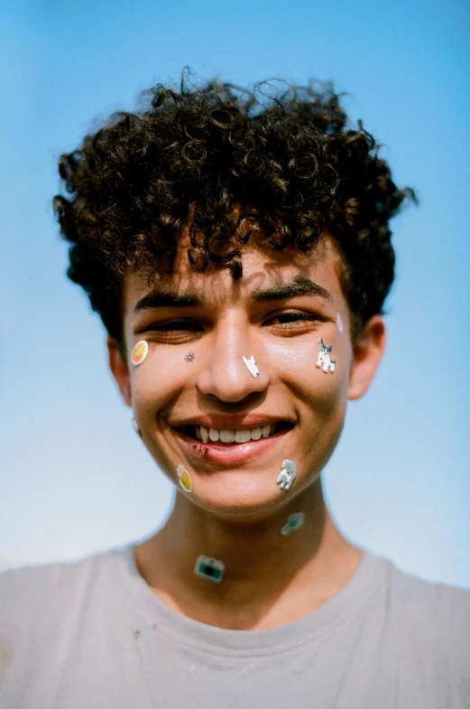 a boy with confetti painted on his face smiling