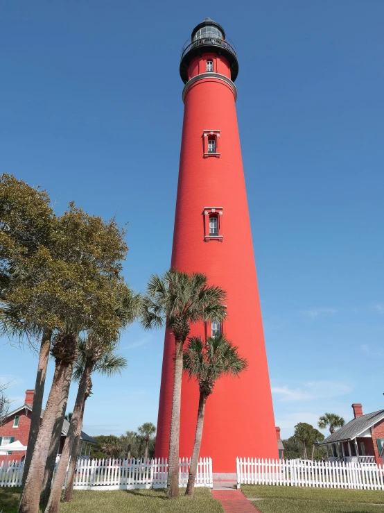 a red tower with two trees near it and a fence around it