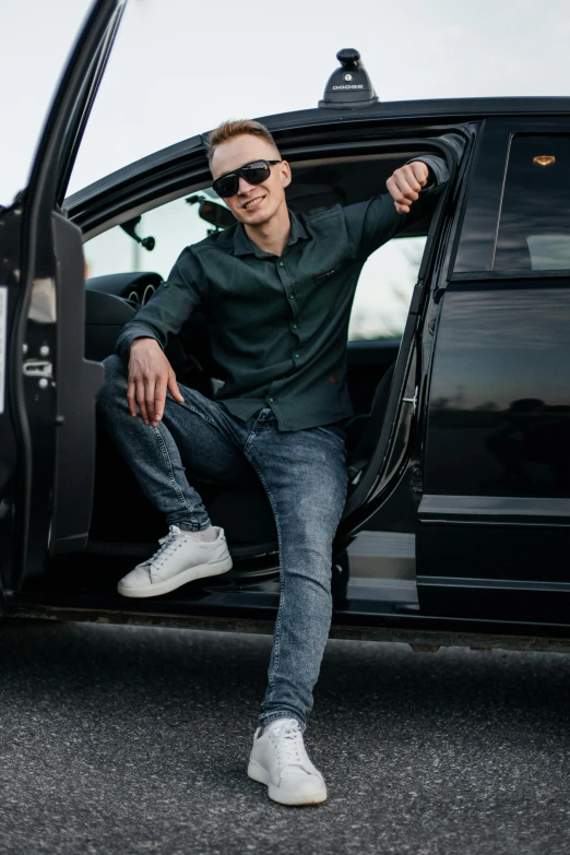 a man wearing sunglasses sits in the door of a limo