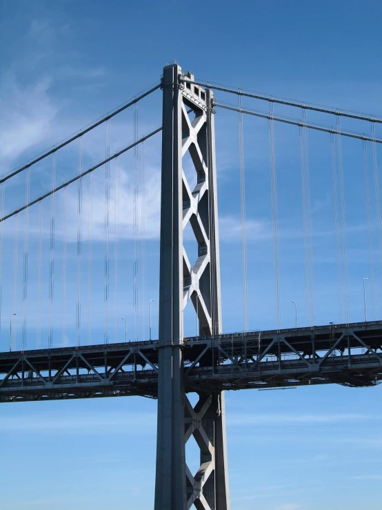 a large bridge with a sky background and a airplane flying over the top