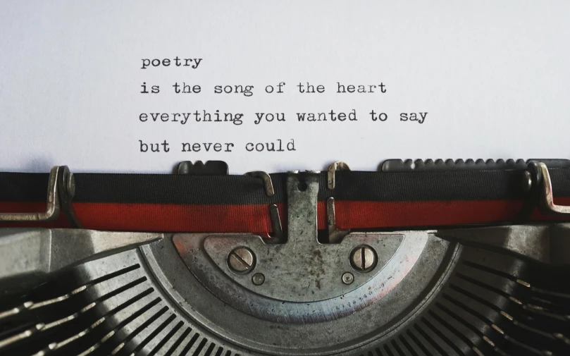 a close up of a typewriter with the words poetry is the song of the heart everything you have to say but never could