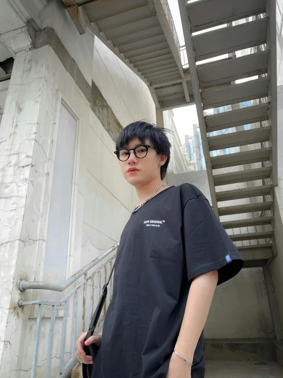 a person standing outside by some stairs wearing glasses