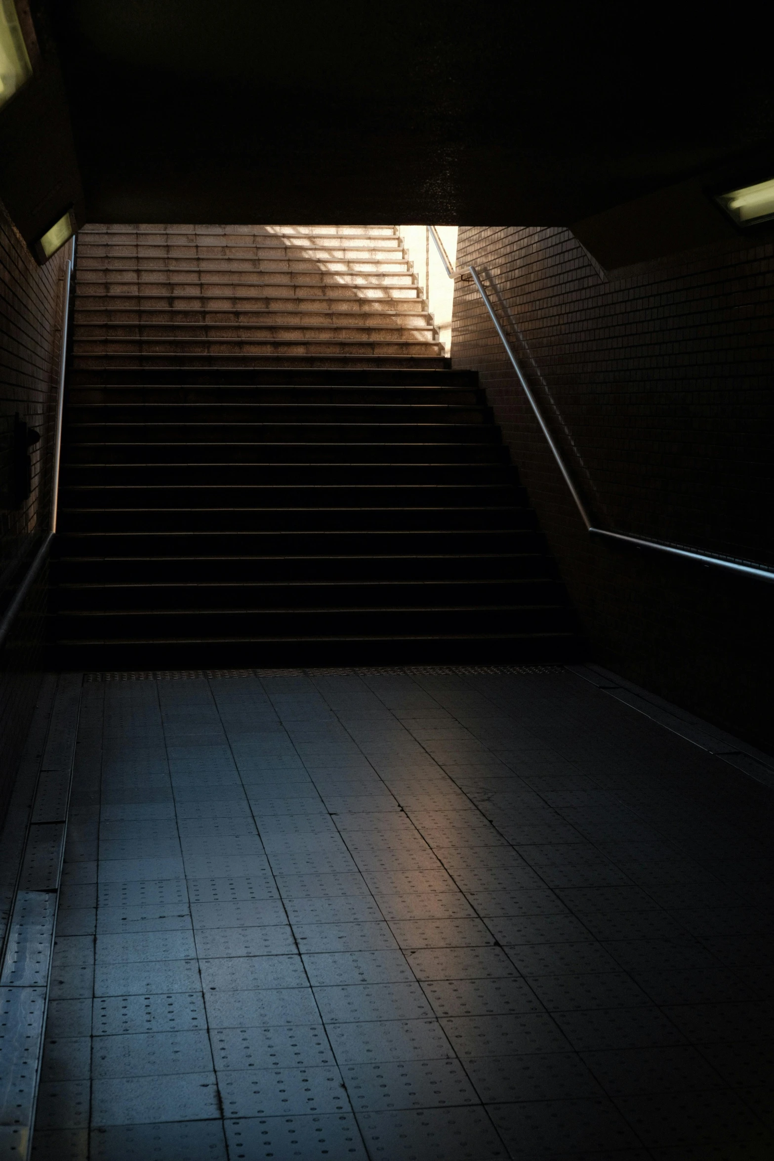 staircases lit by sun shining through them and a dark room with tile flooring