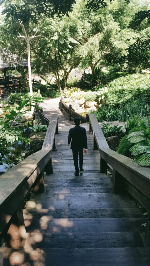 a man in a business suit is walking on a bridge