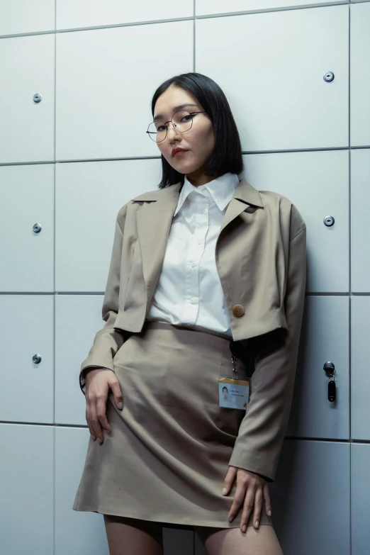 a woman wearing glasses and a skirt standing next to a wall