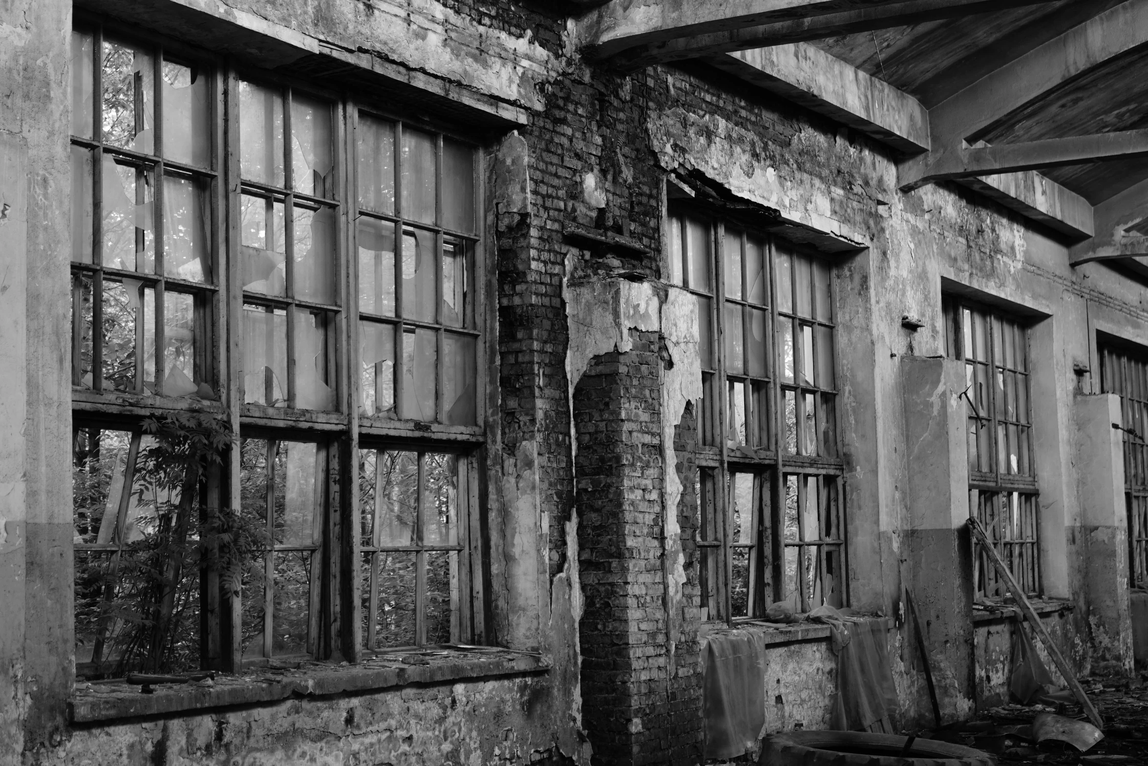 two old windows in an old house with a rusted metal fence